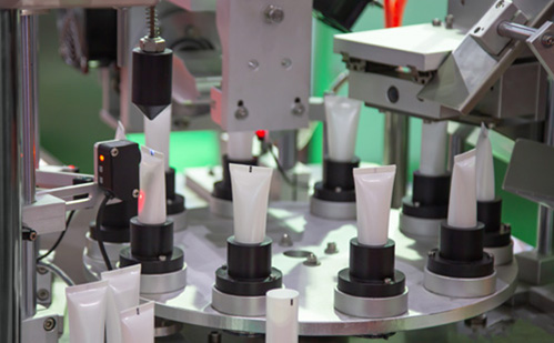 White body lotion containers in machine line up by Currier